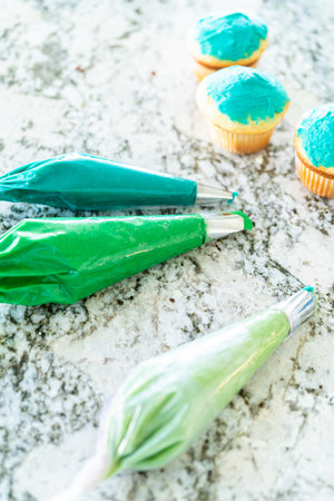Using buttercream frosting, vanilla and chocolate cupcakes are intricately decorated to resemble various types of cactuses, creating a delightful and visually engaging dessert that showcases creativity and skill in baking.の写真素材