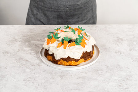 Decorating freshly baked carrot bundt cake with cream cheese frosting with chocolate carrot cake...