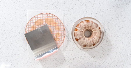 Flat lay. Glazing vanilla bundt cake with a white vanilla glaze.