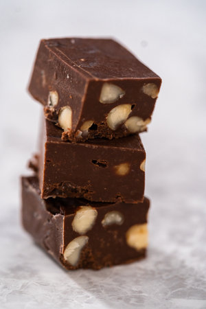 Homemade chocolate macadamia fudge square pieces on a kitchen counter.の写真素材