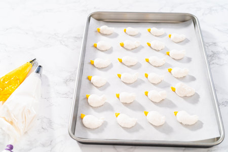 Piping meringue from the piping bags with the metal tip into parchment paper to bake meringue cookies.の写真素材
