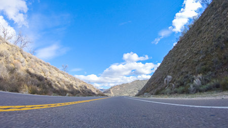 Vehicle is cruising along the Cuyama Highway under the bright sun. The surrounding landscape is illuminated by the radiant sunshine, creating a picturesque and inviting scene as the car travels through this captivating area.の写真素材