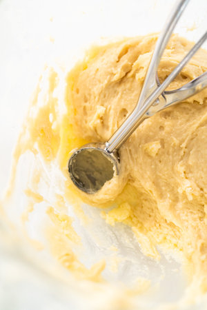 Scooping cupcake batter with dough scoop into a baking pan with liners to bake American flag mini...