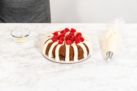 With precision, the White Chocolate Raspberry Bundt Cake is carefully removed from the pan - adorned with luscious cream cheese frosting, creating a delectable treat that is sure to delight.の写真素材