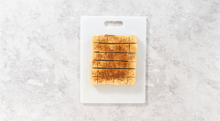 Flat lay. Cutting eggnog fudge into small pieces on a white cutting board.