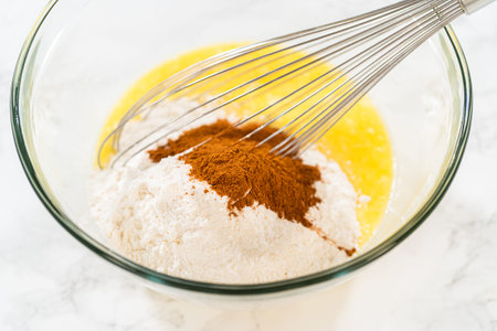 In a large glass bowl, the ingredients are expertly mixed to create the batter for baking the...