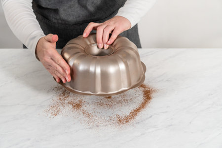 Greasing metal bundt cake pan with vegetable shortening and cocoa powder to bake gingerbread bundt...
