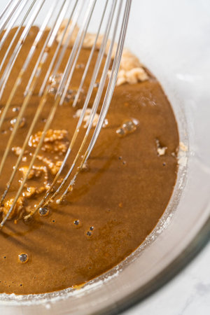 Mixing wet ingredients in a small glass mixing bowl to bake gingerbread bundt cake with caramel...