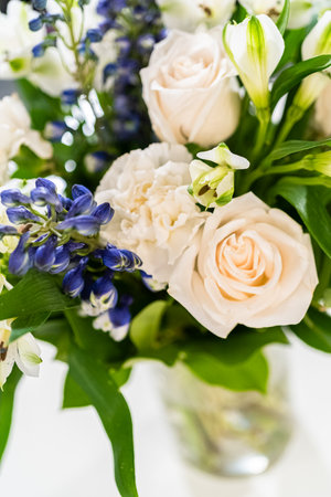 A stunning bouquet featuring fresh white roses and assorted flowers gracefully arranged in a vase, exuding timeless beauty.の写真素材