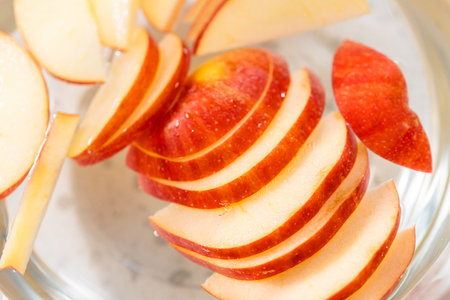 Washing apple slices in the water mixture to prevent them from browning.の写真素材