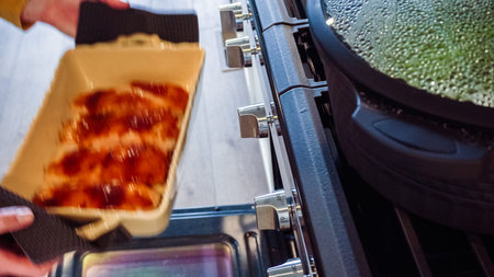 In a white modern kitchen, baked teriyaki salmon is being carefully retrieved from the oven.の写真素材