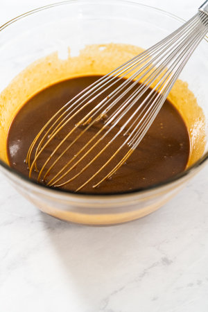 Mixing wet ingredients in a small glass mixing bowl to bake gingerbread bundt cake with caramel fillingの写真素材