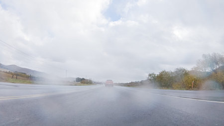 Vehicle navigates the streets of Morro Bay, California, during a cloudy winter day. The atmosphere...