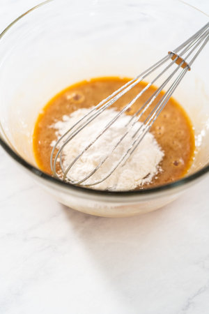 Mixing ingredients with a hand mixer in a small mixing bowl to make the caramel filling for bundt...