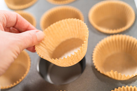 Getting ready to bake delicious chocolate cupcakes, we carefully line the cupcake pan with paper liners, ensuring a delightful treat awaits.の写真素材
