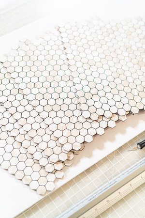 In the process of mounting peel and stick mosaic tiles onto a foam board, perfect for enhancing a...
