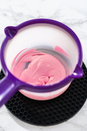Preparing pink chocolate bows to decorate panda-shaped shortbread cookies.