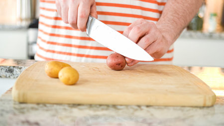 In the contemporary ambiance of a modern kitchen, a young man engages in dinner preparations. His...