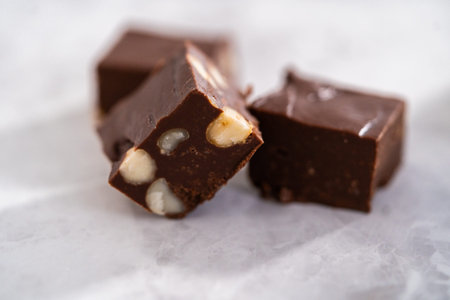 Homemade chocolate macadamia fudge square pieces on a kitchen counter.の写真素材