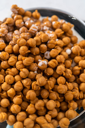 Melting chocolate chips and other ingredients in a glass mixing bowl over boiling water to prepare caramel fudge.の写真素材