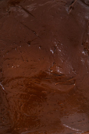 Pouring fudge mixture into the baking pan lined with parchment paper to prepare chocolate fudge with peanut butter swirl.の写真素材