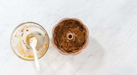 Flat lay. Filling metal bundt cake pan with cake butter to bake gingerbread bundt cake with caramel...