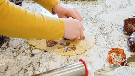 Using various festive cookie cutters, were cutting out charming gingerbread cookies from the rolled dough on the sleek marble counter, bringing holiday cheer to the modern kitchen.の写真素材