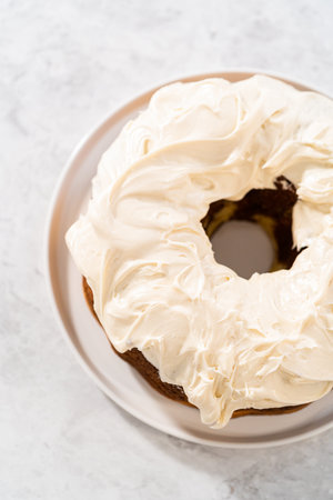 Icing freshly baked carrot bundt cake with cream cheese buttercream.の写真素材