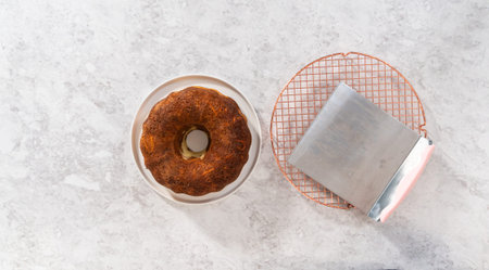 Flat lay. Transferring cooled freshly baked carrot bundt cake from the round cooling rack to the...