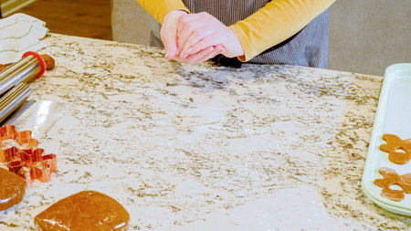 Using an adjustable rolling pin to roll out gingerbread cookie dough on the elegant marble counter in a modern kitchen, getting ready for festive holiday baking.の写真素材