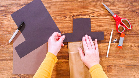 Step by step. Flat lay. Teacher guides online class through making a paper puppet from a brown bag, creatively using a wooden surface as a workspace.の写真素材