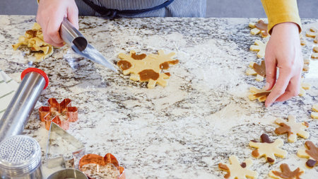 Using various festive cookie cutters, were cutting out charming gingerbread cookies from the rolled...