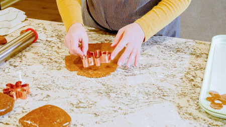Using various festive cookie cutters, were cutting out charming gingerbread cookies from the rolled dough on the sleek marble counter, bringing holiday cheer to the modern kitchen.の写真素材