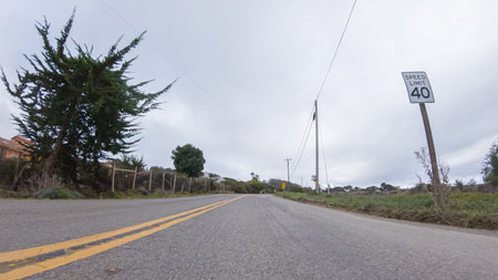 Vehicle navigates the streets of Morro Bay, California, during a cloudy winter day. The atmosphere...