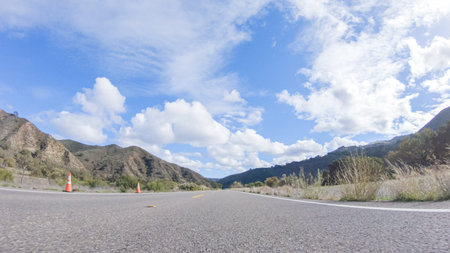 Vehicle is cruising along the Cuyama Highway under the bright sun. The surrounding landscape is...