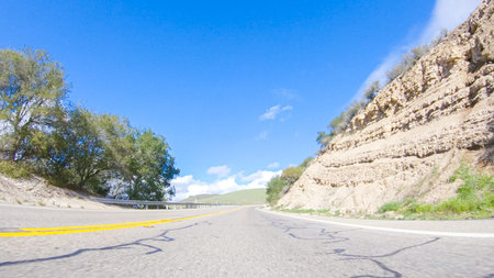 Vehicle is cruising along the Cuyama Highway under the bright sun. The surrounding landscape is...