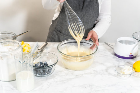 Integrating ingredients in a glass bowl, adeptly stirring with a whisk to craft a tantalizing...