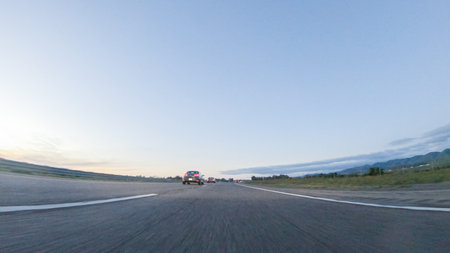 As the sun sets, driving on HWY 101 near Pismo Beach, California becomes a captivating experience with the sky painted in shades of orange and pink, casting a warm glow over the coastal landscape.の写真素材