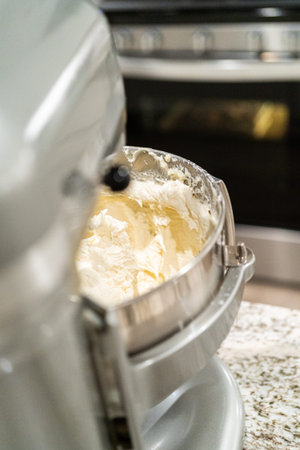Stand mixer whips up creamy buttercream frosting to perfection, ready for dessert decorating.