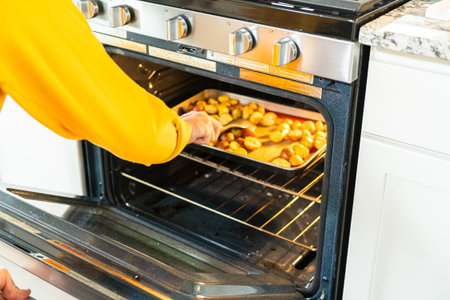 In a modern kitchen, an array of halved, multicolored marble potatoes are arranged on a baking pan...