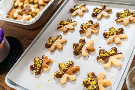 Crafting star-shaped holiday cookies dipped in chocolate and sprinkled with crushed pistachios,...