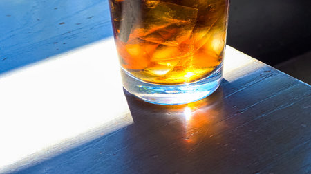 A close-up shot showcases a refreshing glass filled with ice cubes and soda pop, placed on a...