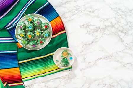 Flat lay. Cactus-shaped cake pops, beautifully decorated with luster dust, sugar flowers, and white sprinkles, arranged in celebration of Cinco de Mayo.の写真素材