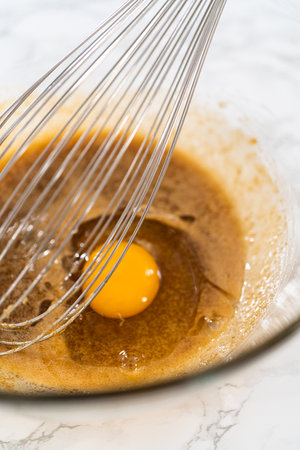 Mixing wet ingredients in a large glass mixing bowl to bake lemon poppy seed muffins.の写真素材