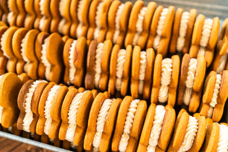Making gingerbread man cookie sandwiches filled with eggnog buttercream, arrayed on a rustic wooden table, ideal for heartfelt Christmas gifting.の写真素材