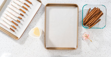 Flat lay. Dipping pretzel rods into melted chocolate and sprinkling with crushed candy cane candies to make candy cane chocolate-covered pretzel rods.の写真素材