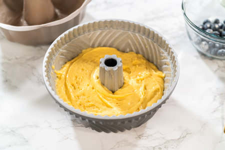 Delicately transferring the cake batter into the pre-greased bundt cake pan, setting the stage for a...