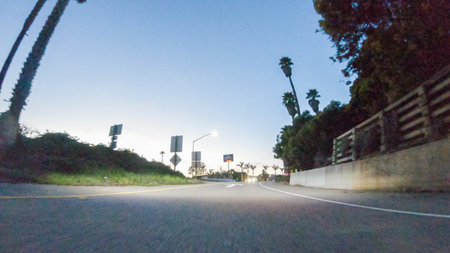 As the sun sets, driving on HWY 101 near Pismo Beach, California becomes a captivating experience with the sky painted in shades of orange and pink, casting a warm glow over the coastal landscape.の写真素材
