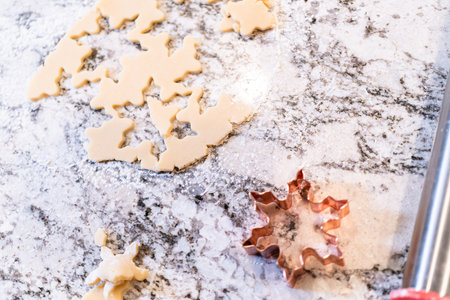 Enjoy the festive tradition of rolling out cookie dough and cutting snowflake-shaped sugar cookies, perfect for the holiday season.の写真素材