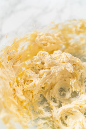 Mixing ingredients in a glass mixing bowl to make the cream cheese frosting for no-yeast cinnamon roll cupcakes.の写真素材